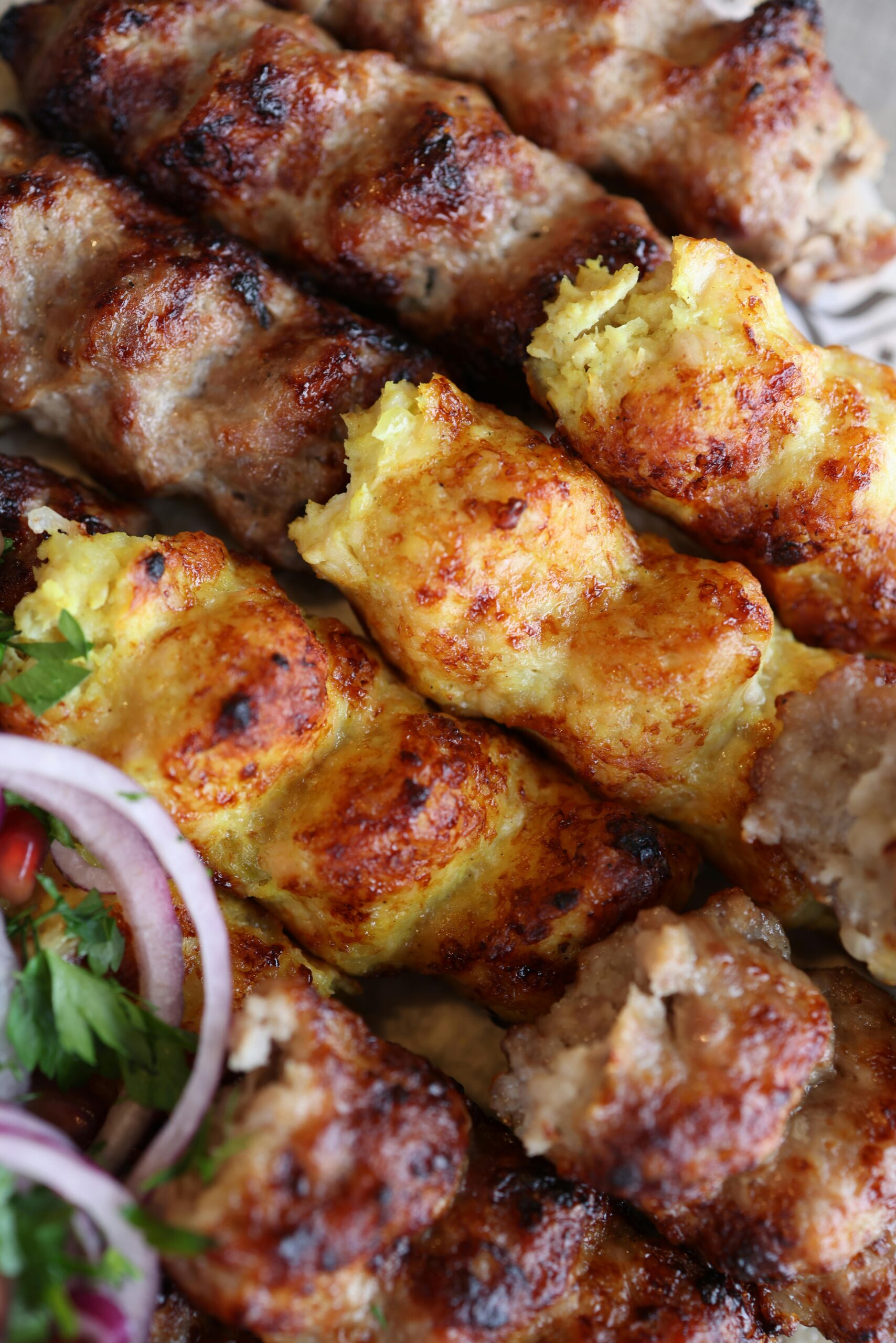 Close-up of juicy mixed kebab skewers with herbs and onions, showcasing gourmet grill marks.